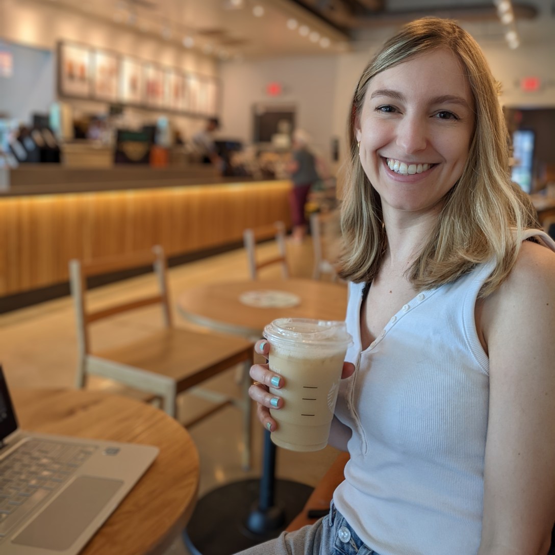 Alexis sits in a coffee shop holding an iced London Fog latte.
