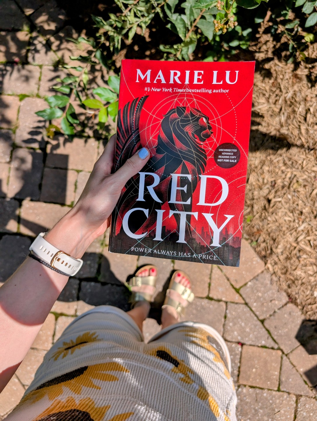 Alexis holds Red City above a stone walkway and a tree