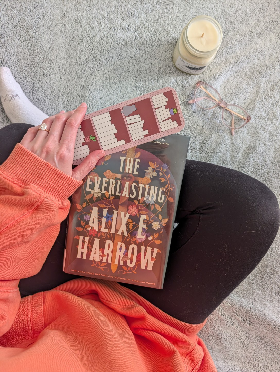 The Everlasting with a bookmark, candle, and glasses